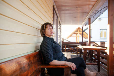 Portrait of beautiful mature woman on porch of her houseの写真素材