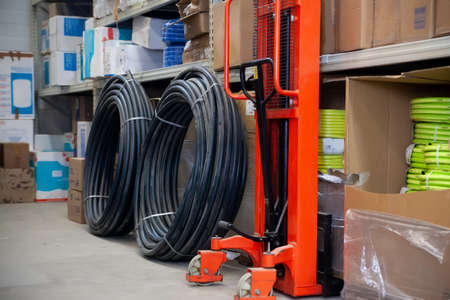 Pvc pipes wound in coils on shelves of store's warehouse.