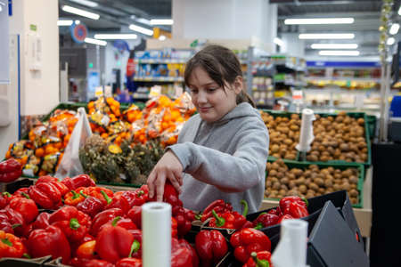 Portrait of smiling cute teen girl in fruit and vegetable department of supermarketの写真素材