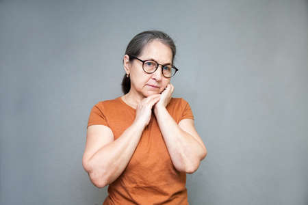 Portrait of serious 60-year-old woman on gray background.の写真素材
