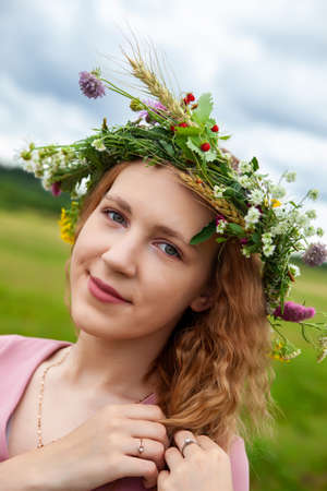 Young girl in wreath of wild flowers outdoors on summer day.の写真素材