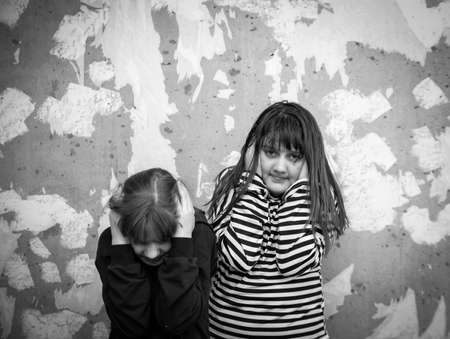 Two little girls standing in embrace at destroyed wall and afraid, concept of latest news in world about Russia's attack on Ukraineの写真素材