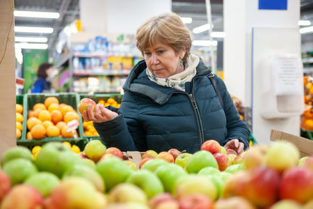 Senior woman picking apple at the grocery storeの写真素材