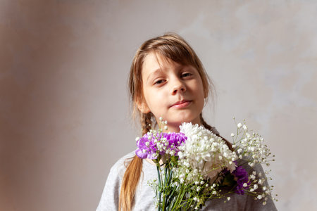 Portrait of pre-adolescent girl on light background with bouquet of flowersの写真素材