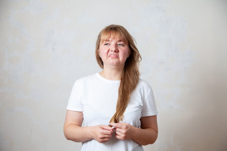 Sad blonde in white T-shirt with frustrated expression on her face.の写真素材