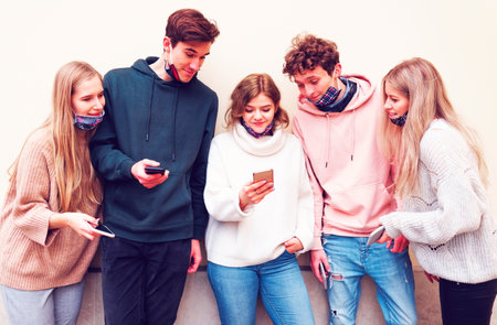 Millennial youngster using mobiles - New normal during pandemic - Fake news   - addicted to technology always connected students. New normal lifestyle concept. friends teenagers fun.の写真素材
