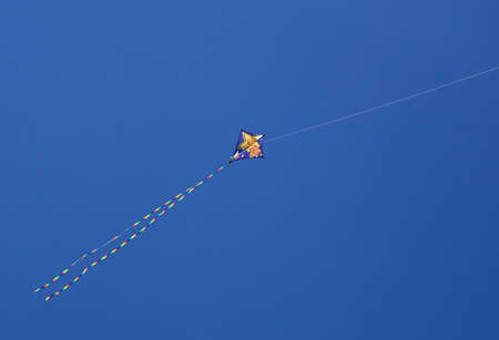 A colourful kite against a vivid blue sky