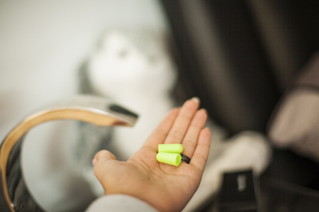 The girl holds the ear plugs in her hand and goes to sleep, against the background of a bed, a...