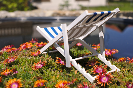 A toy decorations striped beach chair for sunbathing and relaxing is standing near swimming pool, on...