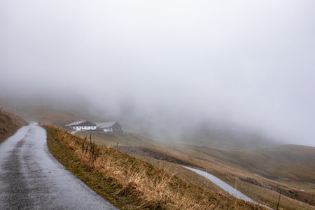 Alpine scenery high in the mountains in autumn, the road in the fog, the texture of stone and grass, clouds envelop the mountainsの写真素材