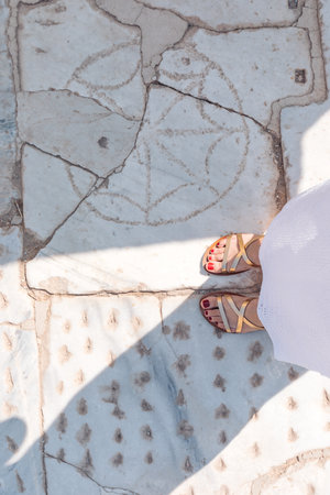 Feet in sandals, homemade dress, white slippery marble in the backgroundの写真素材
