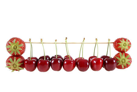 strawberries and cherries suspended on a stick isolated on the white backgroundの写真素材