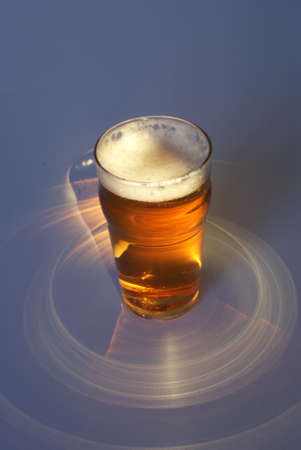glass full of beer on dark background with shadowの写真素材