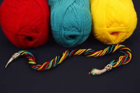 three woolen skeins and snake on black background