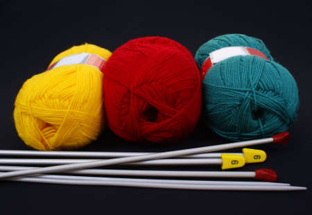 three woolen skeins and knitting needle on black backgroundの写真素材