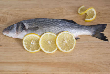 fresh fish and  lemon slices on plank の写真素材