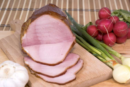 ham cut in slices on board and vegetablesの写真素材