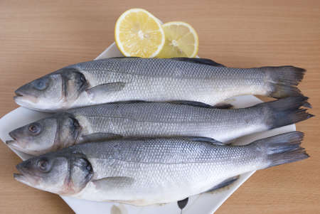 fresh fish and  lemon slices on plateの写真素材