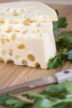 yellow cheese with large holes and parsleyの写真素材