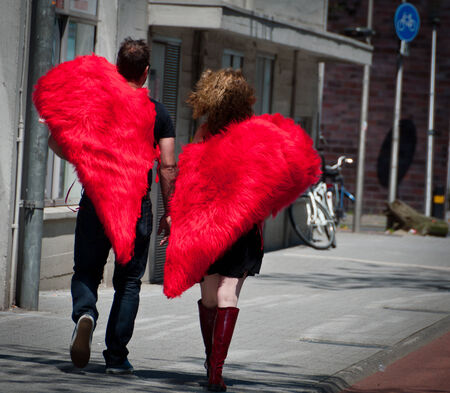 EINDHOVEN, NETHERLANDS - JUNE 8: An adult couple with half-heart shaped costumes walking in the street.のeditorial素材