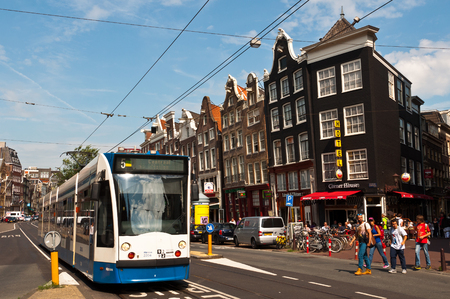 AMSTERDAM, NETHERLANDS - AUGUST 16, 2013: Common view of street in Amsterdam with a tram approaching in summer of 2013.のeditorial素材