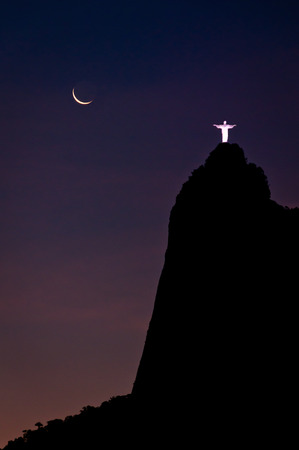Rio de Janeiro, Brazil - December 4, 2013: Spectacular view of illuminated Christ the Redeemer statue on the Corcovado Mountain at night with young moon in the sky.のeditorial素材