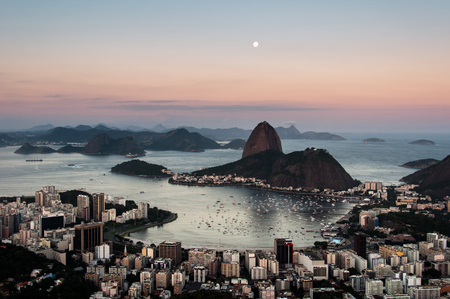 Sugarloaf Mountain and Botafogo Neighborhood in Rio de Janeiro by Sunset with Full Moon in the Sky.の写真素材
