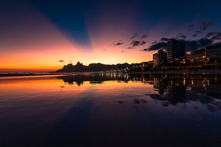 View of Sunset in Ipanema Beach, With Rays of Sun in the Sky, Reflecting in Waterの写真素材