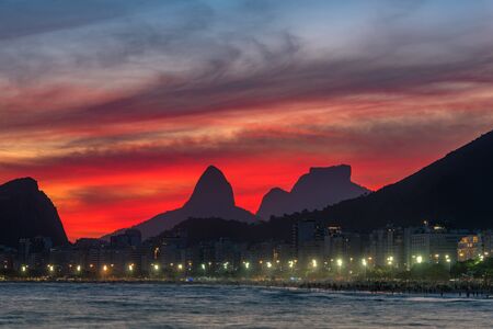 Night View of Copacabana Beach With Beautiful Red Sky Just After the Sunset, and Mountains in the Horizon, in Rio de Janeiro, Brazilの写真素材