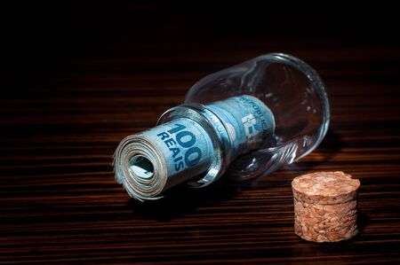 Roll of 100 Brazilian Reais Banknotes Inside a Small Glass Bottle, Saving Moneyの写真素材