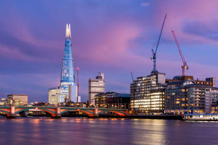 View of London city skyline on colorful sunset, with Southwark bridge over Thames river and the Shard skyscraper in the middle of the frameのeditorial素材