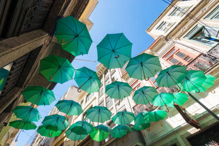 Decorative Green Umbrellas Hanging Between Buildings in the Cityの写真素材