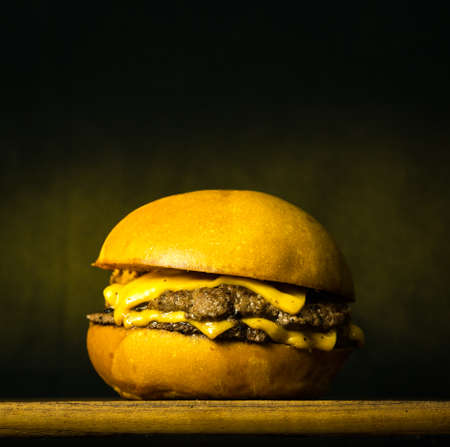Tasty Fresh Home Made Gourmet Burger on Wooden Table With Dark Backgroundの写真素材