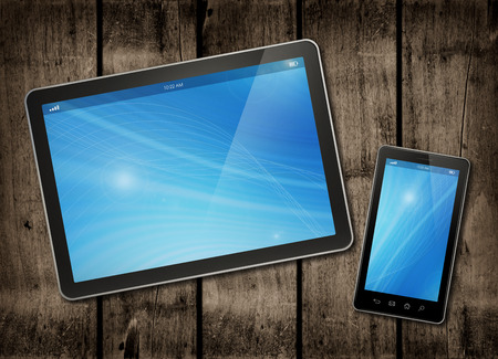 Smartphone and digital tablet PC on a dark wood table - horizontal office mockupの写真素材
