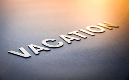 Word vacation written with white solid letters on a boardの写真素材