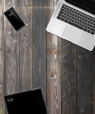 Laptop, tablet and phone set mockup on a wooden desk background. 3D renderの写真素材