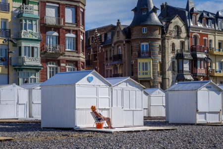 Le-Treport/France - August 11, 2017 : woman sunbathing in front of beach Huts and cityのeditorial素材