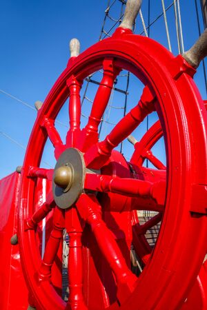 Red wooden wheel helm on antique shipの写真素材