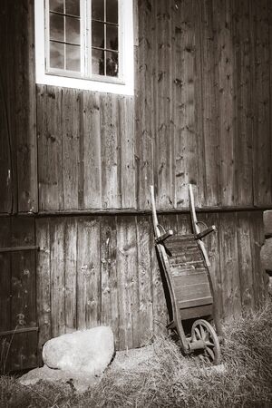Old wooden wheelbarrow on a farm wall. Black and White photographyの写真素材