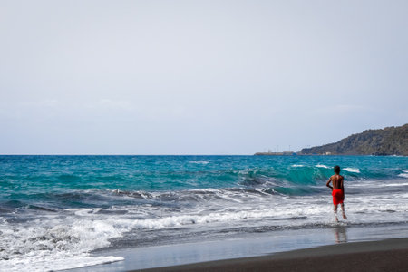 Sao Filipe/Cape Verde - August 7, 2018 - Child playing on a black sand beach in Fogo Islandのeditorial素材