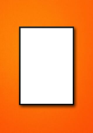 Black picture frame hanging on an orange wall. Blank mockup templateの写真素材