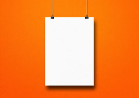 White poster hanging on an orange wall with clips. Blank mockup templateの写真素材