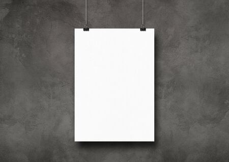 White poster hanging on a dark concrete wall with clips. Blank mockup templateの写真素材