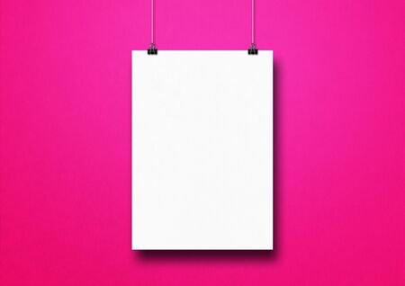 White poster hanging on a pink wall with clips. Blank mockup templateの写真素材
