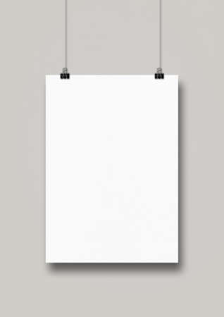 White poster hanging on a clean wall with clips. Blank mockup templateの写真素材