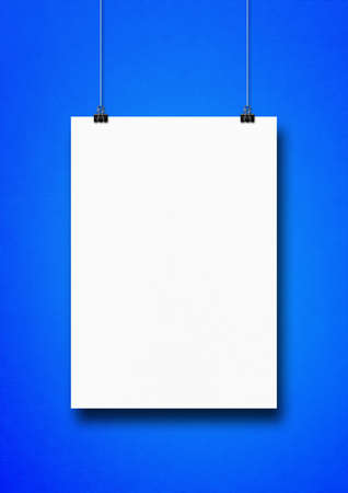 White poster hanging on a blue wall with clips. Blank mockup templateの写真素材
