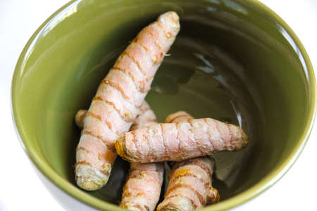 Turmeric root in a bowl isolated on white background. Top viewの写真素材