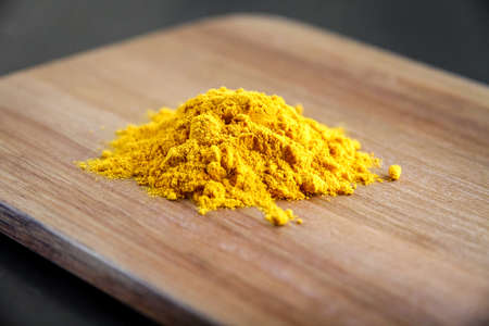 Turmeric spice powder on a wooden cutting board.の写真素材