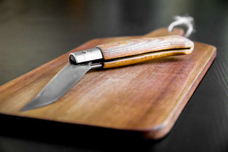 Wooden cutting board and pocket knife on a black kitchen tableの写真素材