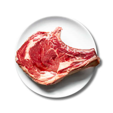 Raw beef prime rib on a plate isolated on white background. Top viewの写真素材